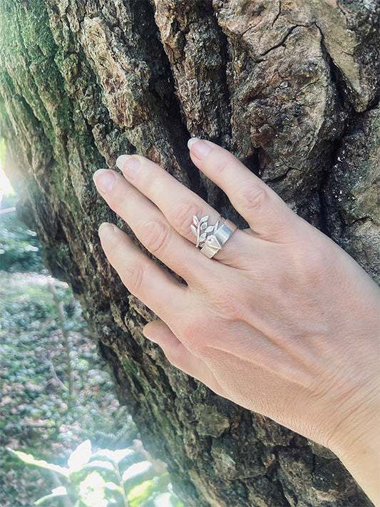 A hand with rings on an oak tree trunk.