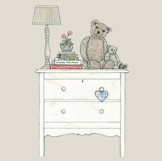 A greetings card featuring 2 bears sat next to a pile of bear books on a chest of drawers