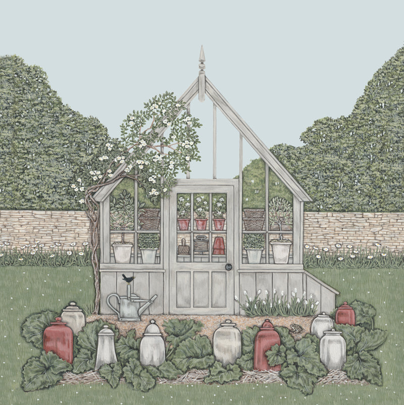 A greetings card featuring a painted wooden greenhouse , partially covered with a climbing rose, with rhubarb forcers in the foreground. A blackbird sat on a watering can, and a frog sat on the gravel infront. Trees in the background.