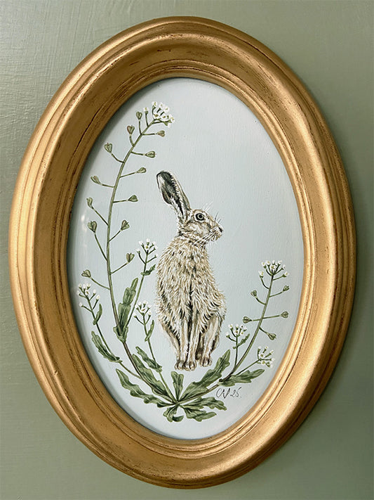 Oval-framed artwork by Sally Swannell of a Hare among Shepherd's Purse on a light blue background
