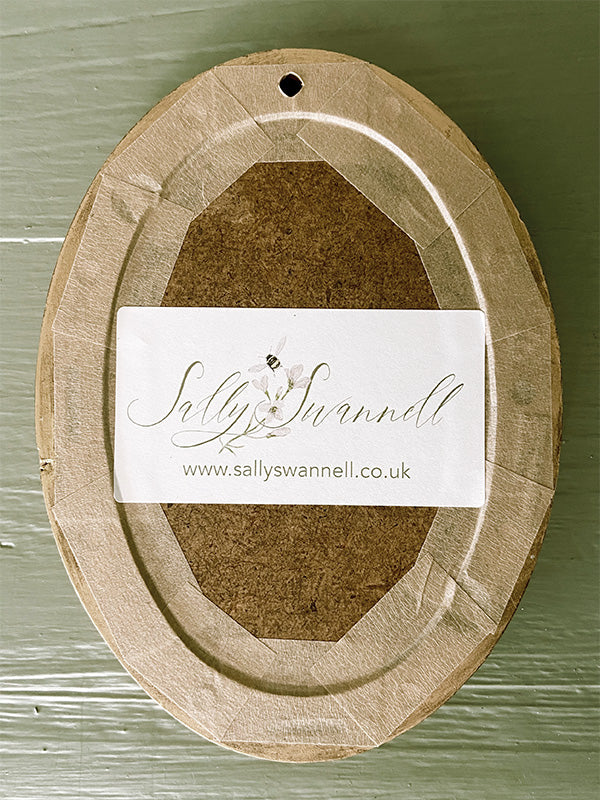 Reverse of a wooden oval frame with a label on a green background