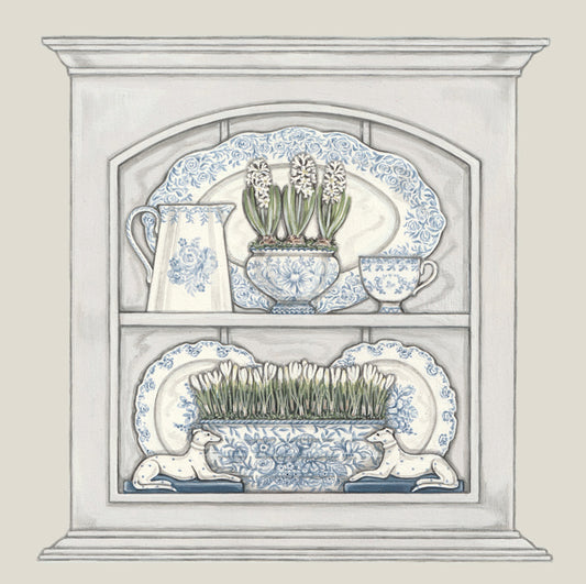 A greetings card featuring a little cupboard filled with blue and white china. A jug, a cup, plates, hyacinth bowl, crocus bowl and 2 china dogs