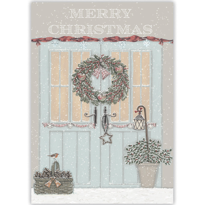 A Christmas-themed card featuring a snowy scene with a light blue front door decorated with a green wreath, red ribbon garland, a hanging lantern, a pot of holly branches, and a robin sat on a  basket of fir cones. The words “MERRY CHRISTMAS” appear at the top.