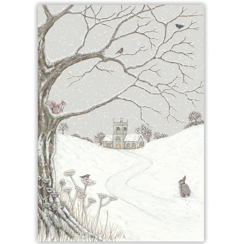 A winter landscape Christmas card featuring a snow-covered hill with a small church in the distance, bare tree branches overhead, birds, a red squirrel, and a rabbit in the foreground.