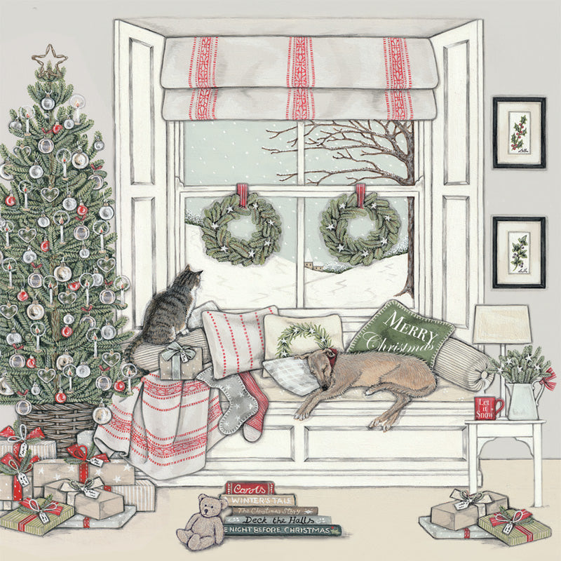 A cosy illustrated Christmas window scene with a cat sitting on a window seat beside a wrapped gift, a dog lying on a cushion that says Merry Christmas, a Christmas tree, wreaths on the window, wrapped presents, framed wall art, and a small teddy bear on the floor.