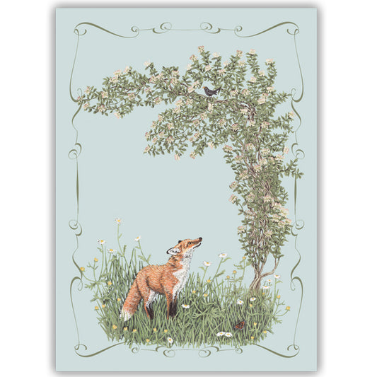 An illustrated card of a fox standing in wild flowers looking up at a blackbird perched in honeysuckle, on a light blue background.