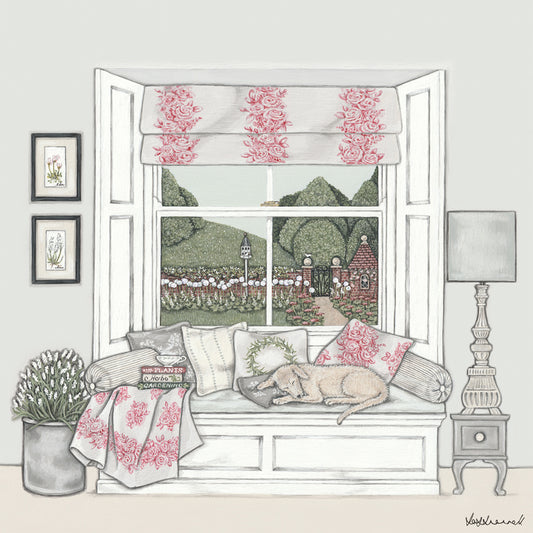 Giclee print of a window seat set in a bay sash window, topped with cushions, and a sleeping dog. Pictures on the wall, a large flower arrangement, side table, lamp, books and cup of tea in the room. The window overlooks countryside, a walled garden containing alliums and a dovecote.